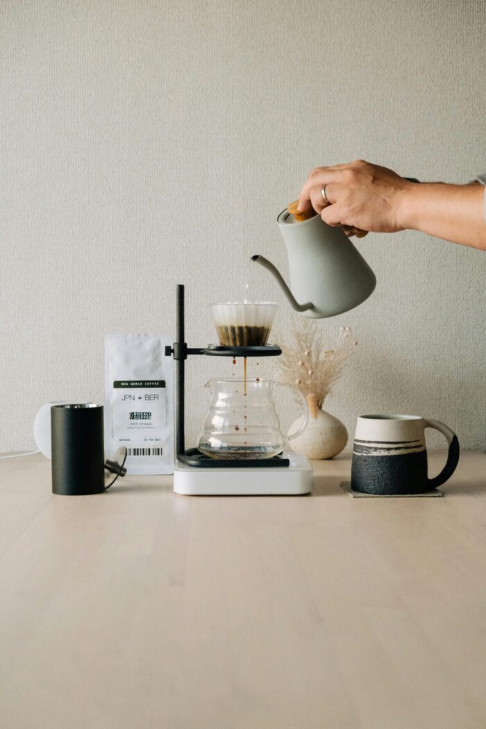 A hand pours water into a coffee filter using a kettle for pour-over brewing setup.