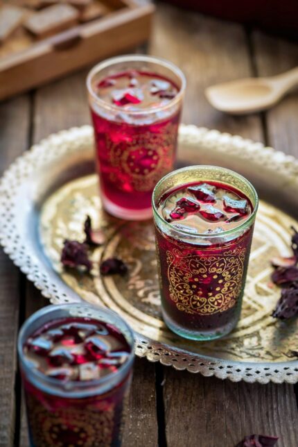 Traditional hibiscus tea served in elegant glasses on a rustic tray, perfect for a refreshing drink.